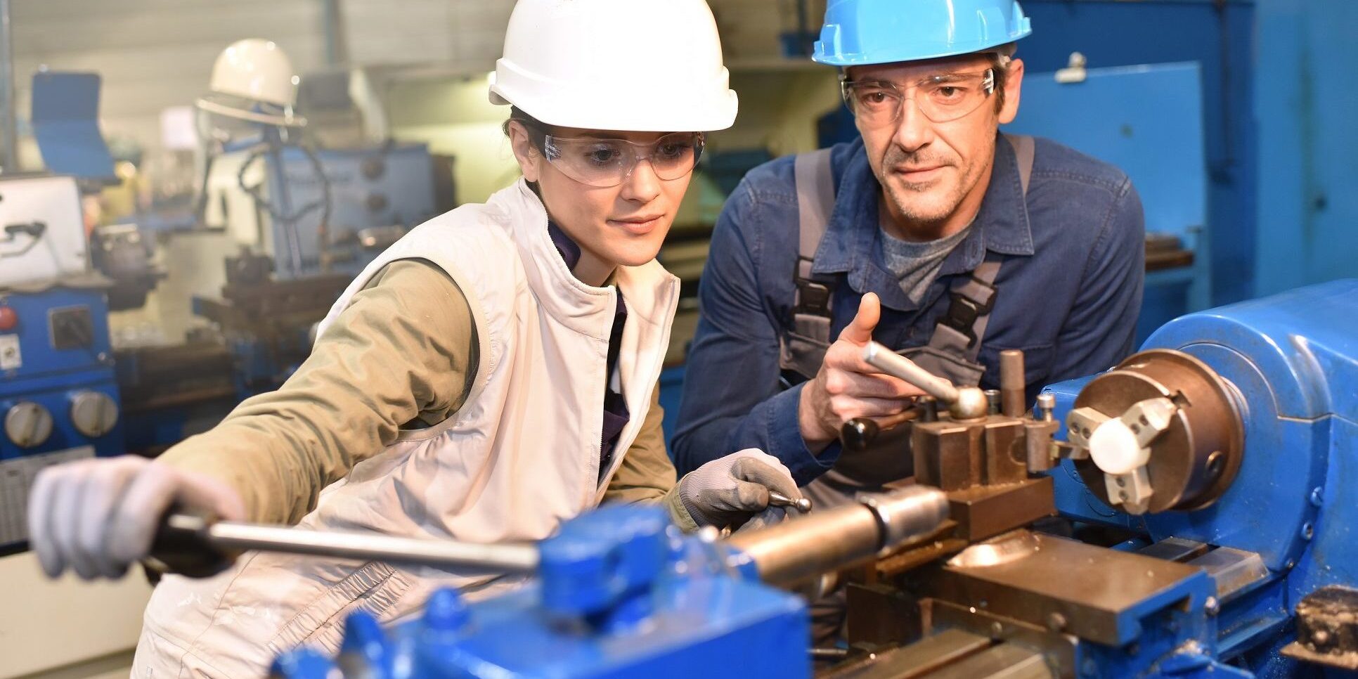 Metal-worker-teaching-trainee-on-machine-use