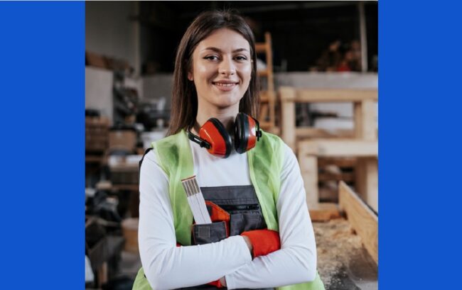 female carpenter with safety ear muffs around neck and arms crossed