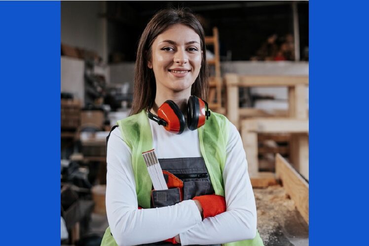female carpenter with safety ear muffs around neck and arms crossed