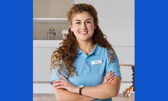 young woman, named Elia, smiling with arms crossed