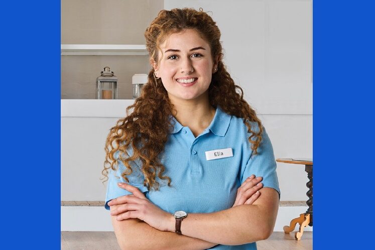 young woman, named Elia, smiling with arms crossed
